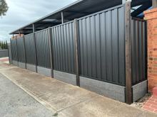 Black Ash woodgrain steel fence on a concrete plinth beside a brick wall