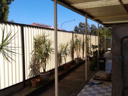 New cream Colorbond privacy fence along the same patio line with potted plants