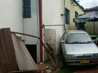 Brown Colorbond sheets and a bent rail down beside a parked car and house wall