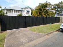 Black Ash woodgrain steel fence with a matching sliding gate across a driveway