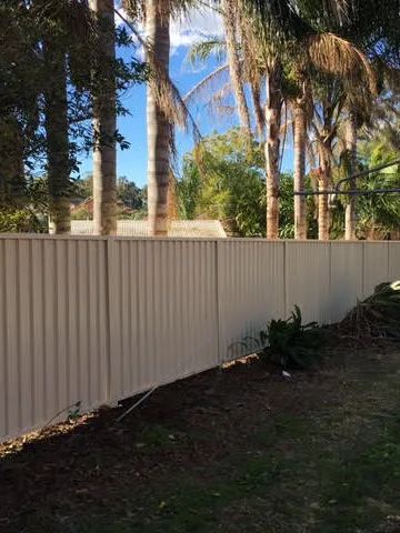 Installed Colorbond sheets running beside lawn and planting.