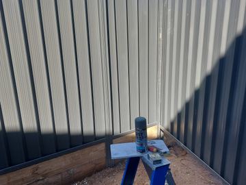 Close view of dark Colorbond privacy sheets with a sawhorse at the base