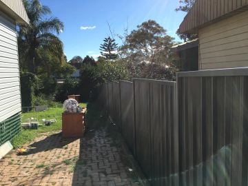 Charcoal Colorbond privacy fence running down the side of a house to the backyard