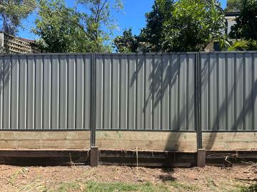 Mid grey Colorbond privacy fence sitting on a timber sleeper retaining wall