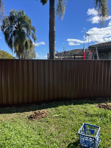 Close view of brown Colorbond privacy sheets along a backyard boundary