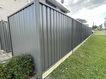 Charcoal Colorbond privacy fence turning the corner of a grassed street boundary