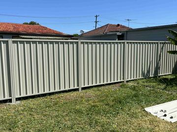 Cream Colorbond privacy fence across a suburban front lawn