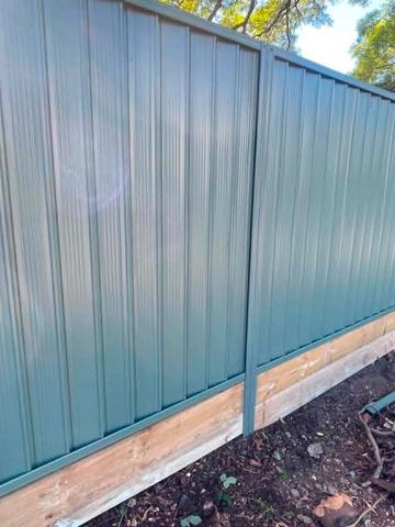 Teal Colorbond privacy fence along a cleared dirt yard