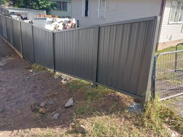 Charcoal Colorbond privacy fence with a temporary mesh gate at the end of the run