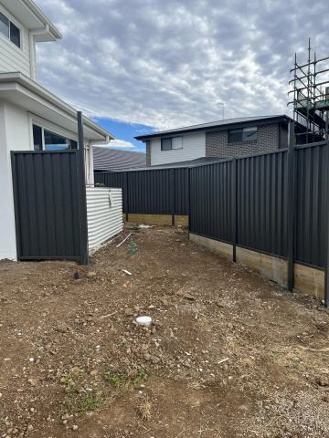 Black Colorbond privacy fence and matching pedestrian gate on a new house block