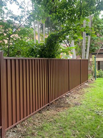 Brown Colorbond privacy fence on a lawn in front of townhouses