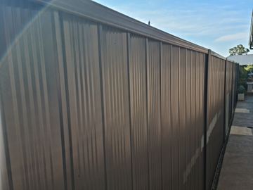 Close view of dark bronze Colorbond privacy sheets along a boundary