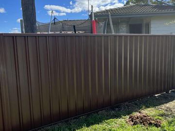 Brown Colorbond privacy fence on a dirt backyard