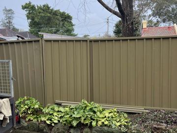 Olive Colorbond privacy fence beside a leafy garden bed