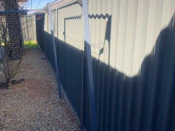 Pale Colorbond privacy fence standing on a gravel yard