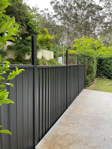 Charcoal Colorbond privacy fence turning a corner beside a garden path