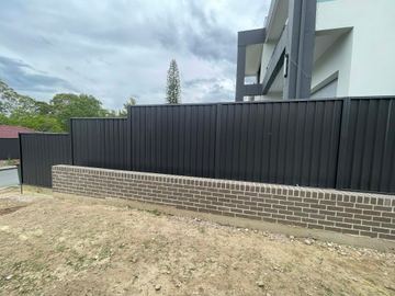 The scene shows a mid grey corrugated steel fence where sleepers form the base.