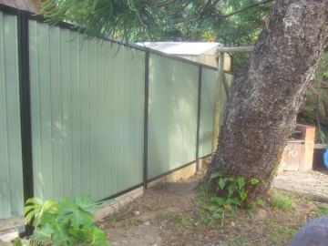 The scene shows a mid grey corrugated steel fence where sleepers form the base.