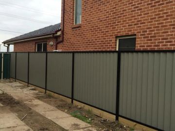 Installed brown Colorbond sheets sitting on a timber sleeper wall.