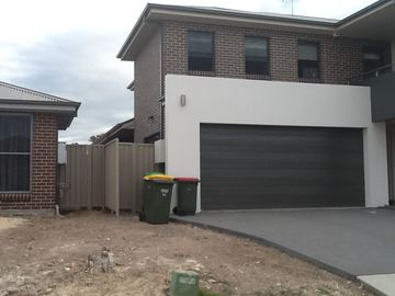 Cream Colorbond pedestrian gate beside a roller-door garage on a new driveway
