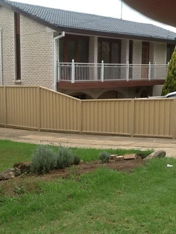 The scene shows a brown corrugated steel fence where sleepers form the base.