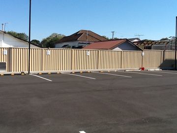Cream Colorbond privacy fence running the length of a marked carpark