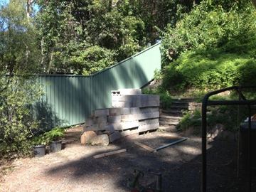 Pale Colorbond privacy fence on a sloped garden with concrete sleeper steps and a black hoop