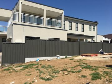 Charcoal Colorbond privacy fence in front of a new dual-occupancy house