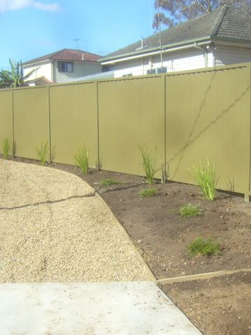 Olive Colorbond privacy fence along a gravel driveway