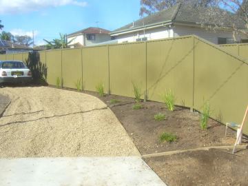 Olive Colorbond privacy fence along a gravel driveway