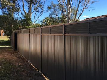 Charcoal Colorbond privacy fence with a horizontal slat topper along a garden boundary