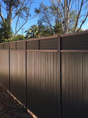 Charcoal Colorbond privacy fence with a horizontal slat topper along a garden boundary