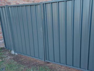 Monument panels line turned soil beside a blended red and tan brick wall without lattice or gates in view.