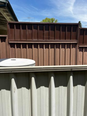 Medium-brown lower panels continue upward with darker chocolate extension sheets above a cream fence in the foreground.