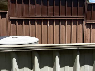 Medium-brown lower panels continue upward with darker chocolate extension sheets above a cream fence in the foreground.