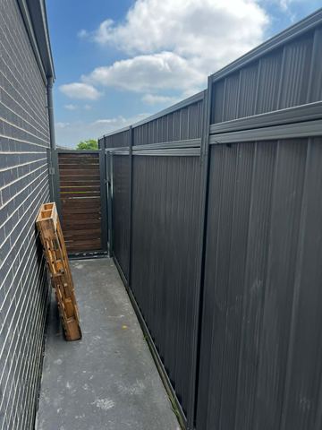 Charcoal Colorbond privacy fence with a timber side gate in the corner
