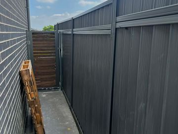 Charcoal Colorbond privacy fence with a timber side gate in the corner