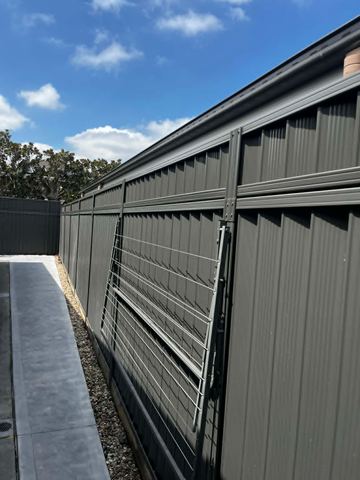 Charcoal Colorbond fence with a slatted screen bay along a paved side path