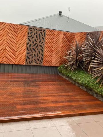 Timber herringbone screen with a decorative metal inlay panel beside a polished timber deck