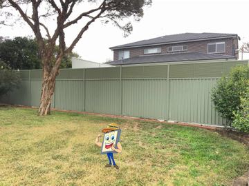 Sage panels with slat tops and brick edging stand before a two-storey brick house and paperbark tree.