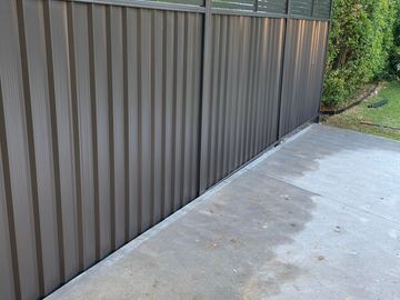 Mid grey Colorbond privacy fence enclosing a freshly poured concrete slab