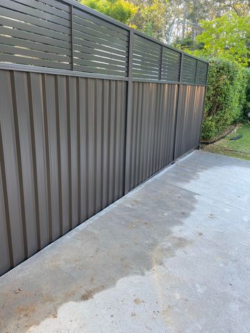 Mid grey Colorbond privacy fence enclosing a freshly poured concrete slab