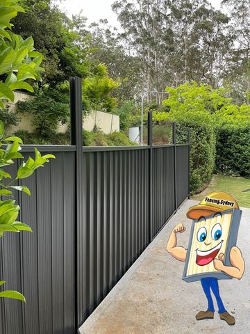 Charcoal Colorbond privacy fence along a paved path with garden planting beside it
