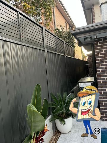 Charcoal Colorbond fence with a slat topper returning against a brick house wall