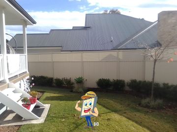 Cream Colorbond privacy fence behind a lawn and a two-storey house balcony
