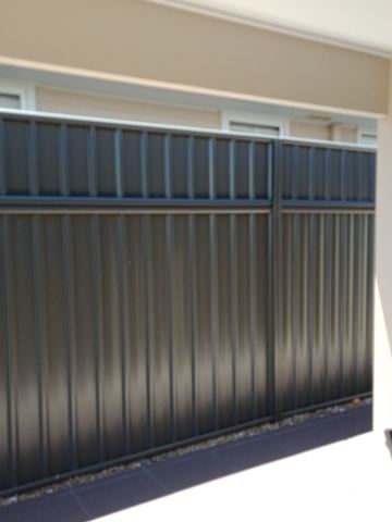 Charcoal Colorbond privacy fence running under a covered patio