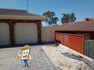 Cream side gate meets long terracotta-brown panels on grey concrete sleepers above white gravel and paver drive.