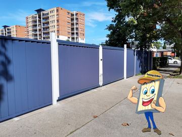 Blue Colorbond sliding driveway gate on a concrete apron in front of apartments