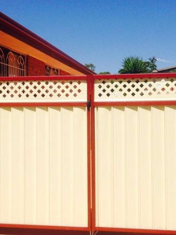 Cream Colorbond double gate with lattice toppers and a red frame under a porch