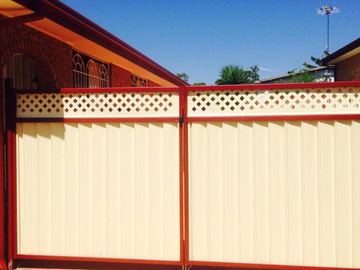 Cream Colorbond double gate with lattice toppers and a red frame under a porch